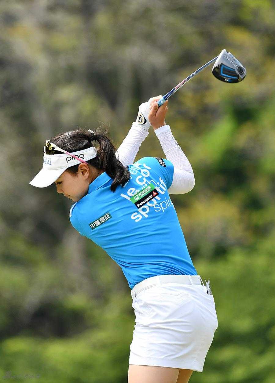 选手在球道中央使用球道木杆攻果岭，杆头划过草皮瞬间，泥土微扬，充满力量感。