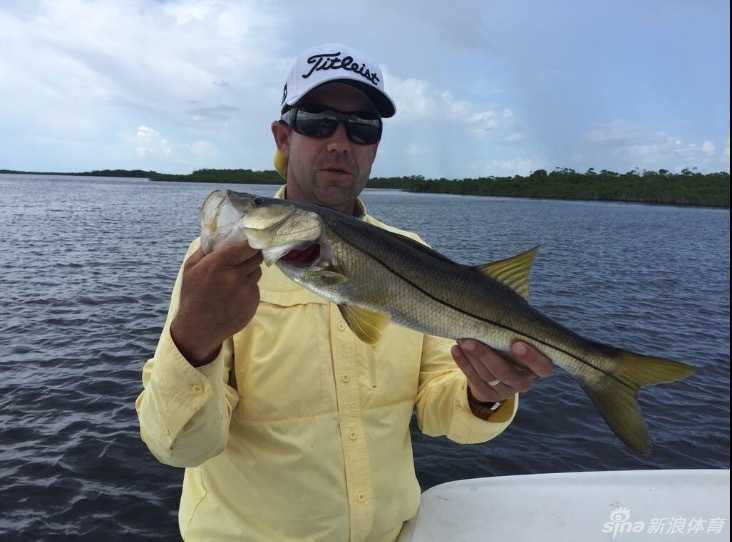 艾里克-康普顿站在小渔船甲板上，手持渔获展露满足笑容，背后是蔚蓝开阔的海面