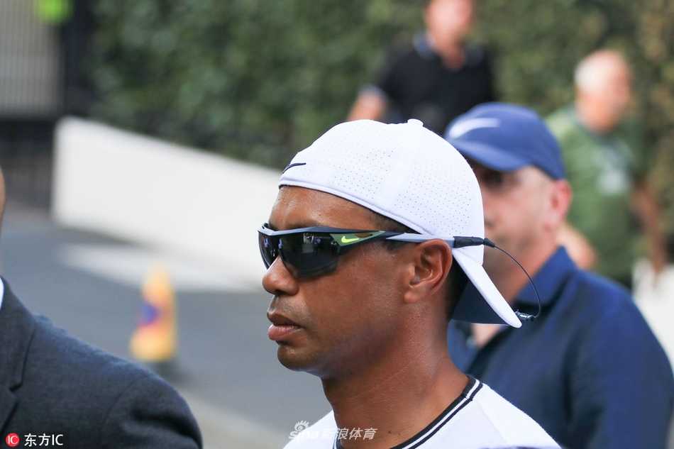 老虎伍兹与一名女性友人并肩走在温网场外，两人正在轻松交谈，气氛融洽