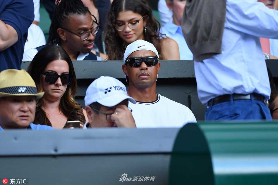 温网赛场边，老虎伍兹面色凝重，紧抿双唇，全神贯注于网球场上的精彩拉锯战