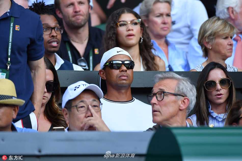 镜头捕捉到伍兹侧身与同伴交流的瞬间，手指轻轻比划，似乎在分享他对刚结束一球的见解