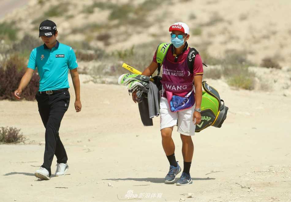 西班牙新星阿若斯在第十八洞果岭边观察线路，背后是标志性的多哈高尔夫俱乐部会所。