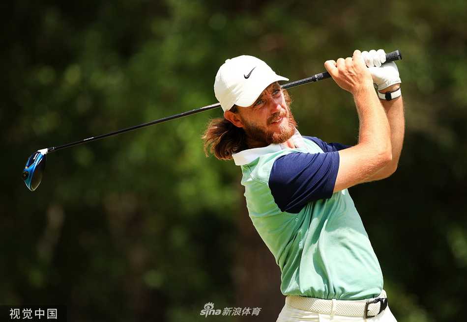 达斯汀·约翰逊在球道上进行击球准备，阳光洒在球场上，他的表情冷静而专注。