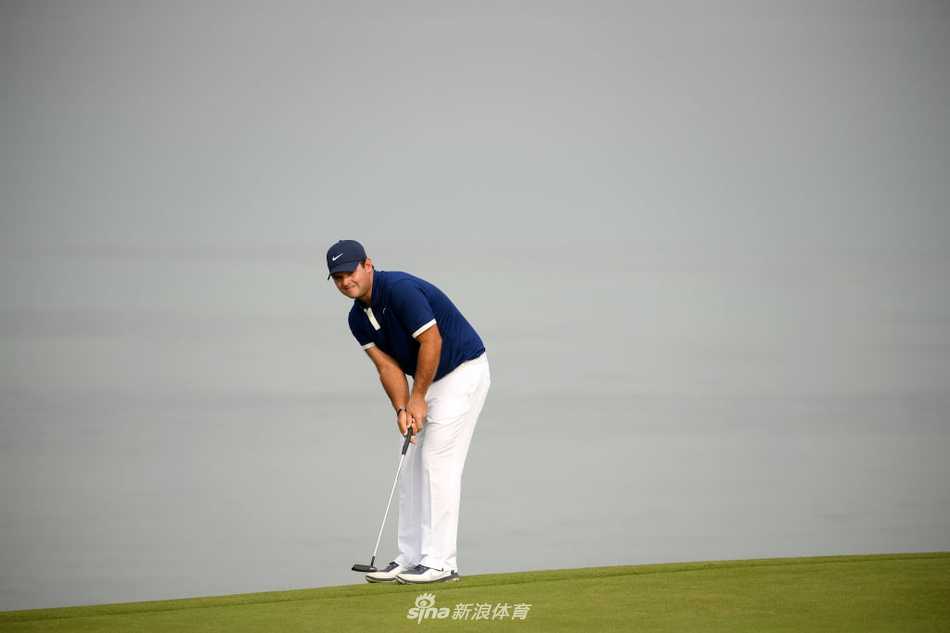 中国名将李昊桐在果岭边专注审视推杆线路，神情坚毅，正为冲击领先位置做关键准备