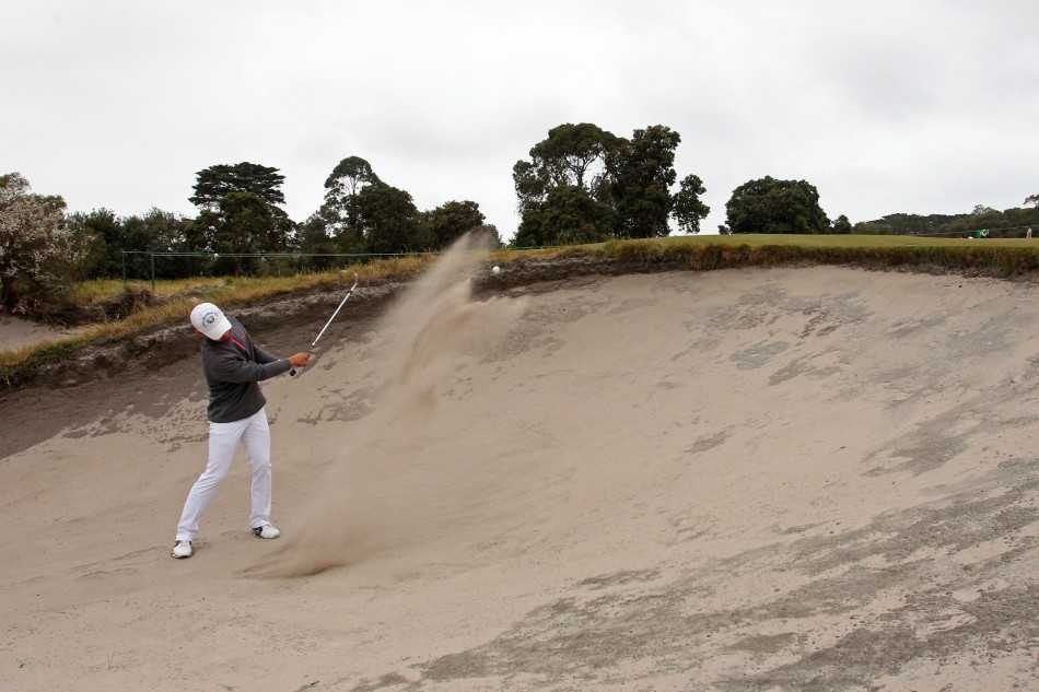 金诚在果岭上推杆后专注凝视小球滚向洞杯，表情沉稳，感受着推击的细微手感与成败