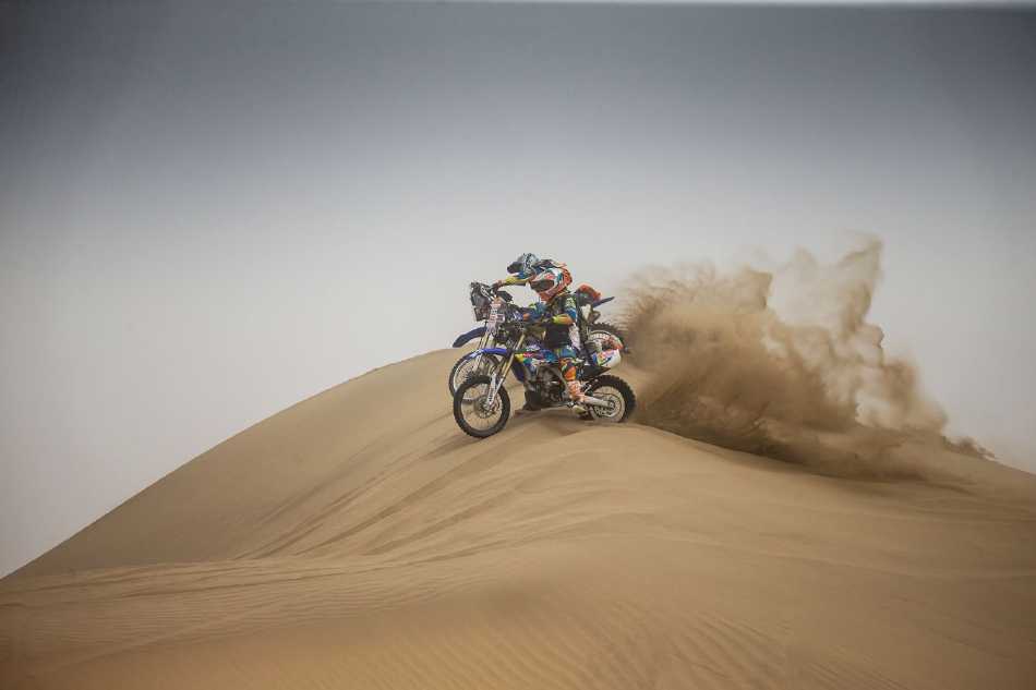 赛车高速掠过沙丘边缘，车身侧倾，在柔软沙面上划出一道坚定而有力的弧形轨迹，动感十足。