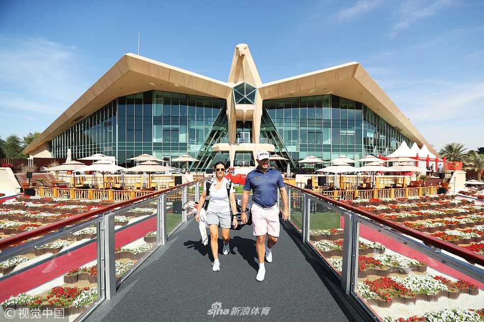 阿布扎比高尔夫俱乐部全景，翠绿球道如丝带般蜿蜒在金色沙漠中，与蔚蓝湖泊和现代建筑相映成趣