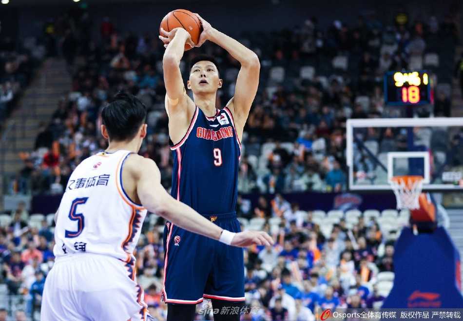 上海男篮球员王哲林在油漆区遭遇广东队易建联与胡明轩的严密包夹，他咬紧牙关奋力高举手臂，试图在人缝中寻找出手空间，肌肉碰撞的火花仿佛要溢出屏幕。