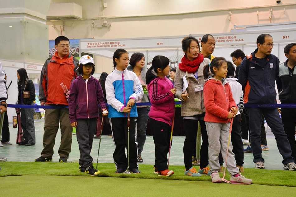 小球员们在练习果岭上认真推杆，阳光勾勒出他们年轻的身影，绿草如茵的背景充满生机。