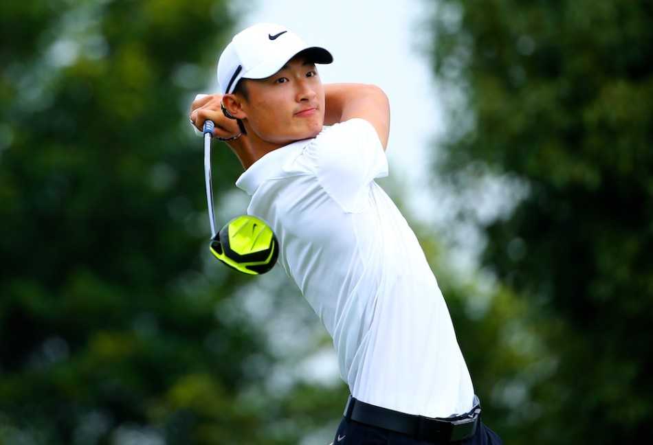 球道沙坑中，球员赵雄一正专注救球，沙坑杆溅起一片细沙，画面极具动感