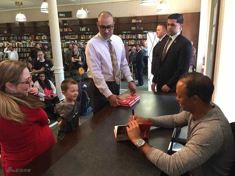 泰格·伍兹在签售会上亲切为粉丝签名，神情专注而平和，展现其作为体坛偶像的亲民一面。