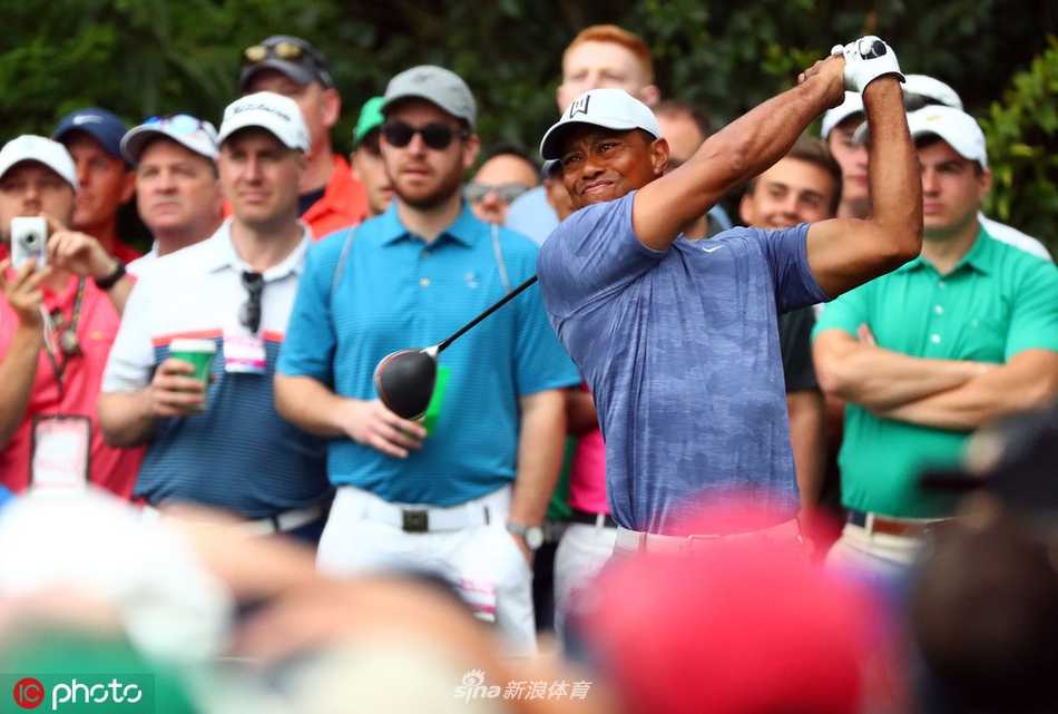 老虎伍兹与贾斯汀托马斯在奥古斯塔球道上并肩前行，认真讨论下一杆的策略，阳光将他们的身影拉长