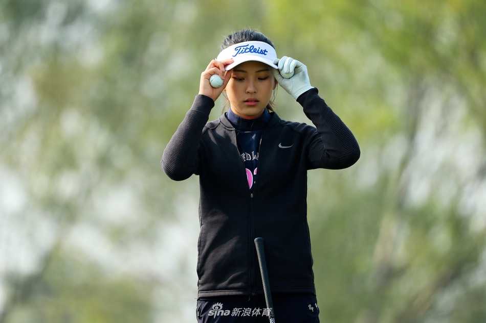 她与同行选手并肩行走于球道，青春的身影在辽阔的蓝天绿草间显得格外朝气蓬勃