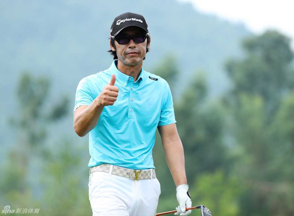 高尔夫球员王长伟在果岭上成功推入一记小鸟球后，正微笑着俯身从球洞中拾起那颗为他带来荣耀的白色小球。