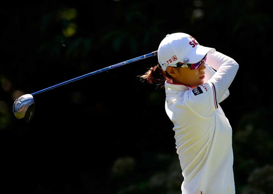 崔罗莲与身旁的球童低声密切交流，商讨策略，默契的团队配合是赛场成功不可或缺的一环。