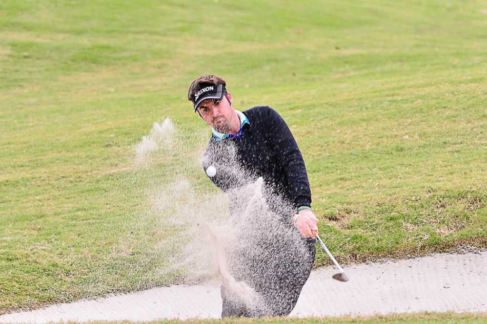 球手Brett在沙坑中沉稳救球，沙粒飞扬间尽显扎实功底与专注神情。