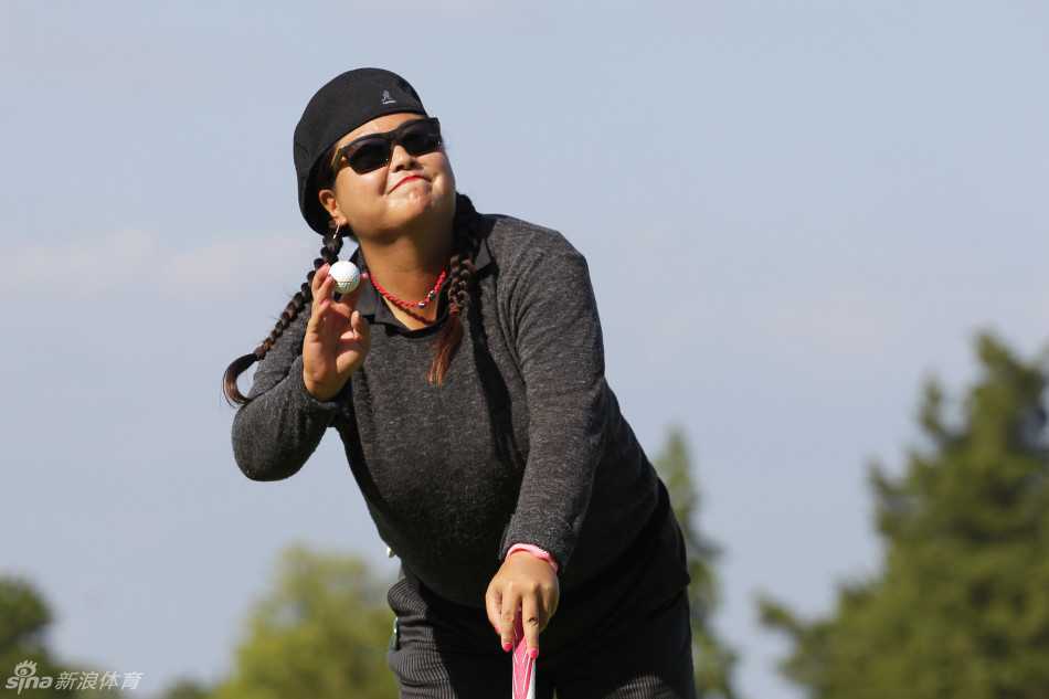 美国名将史黛西·路易斯在果岭上俯身细致观察推杆线路，表情沉着而专注。