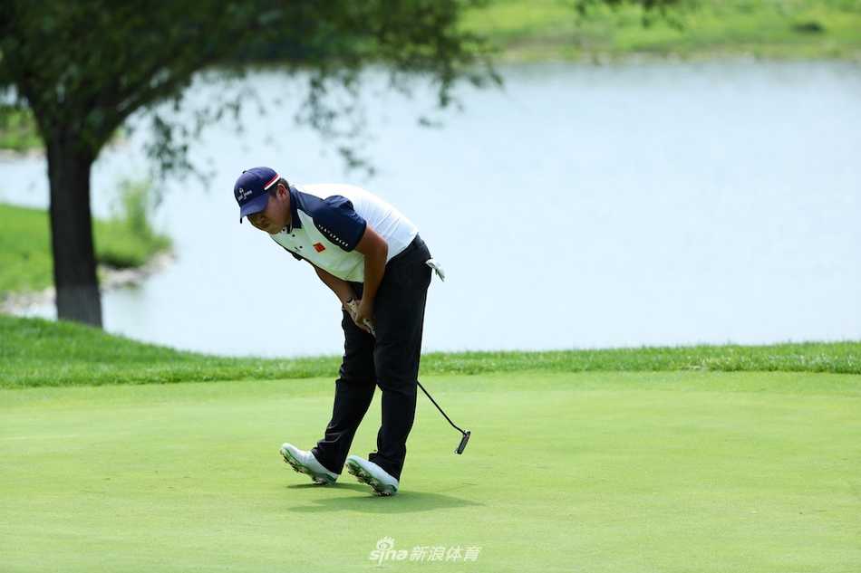佐藤太平在果岭边单膝跪地，神情专注地研究手中码数本，谋划下一杆的进攻策略
