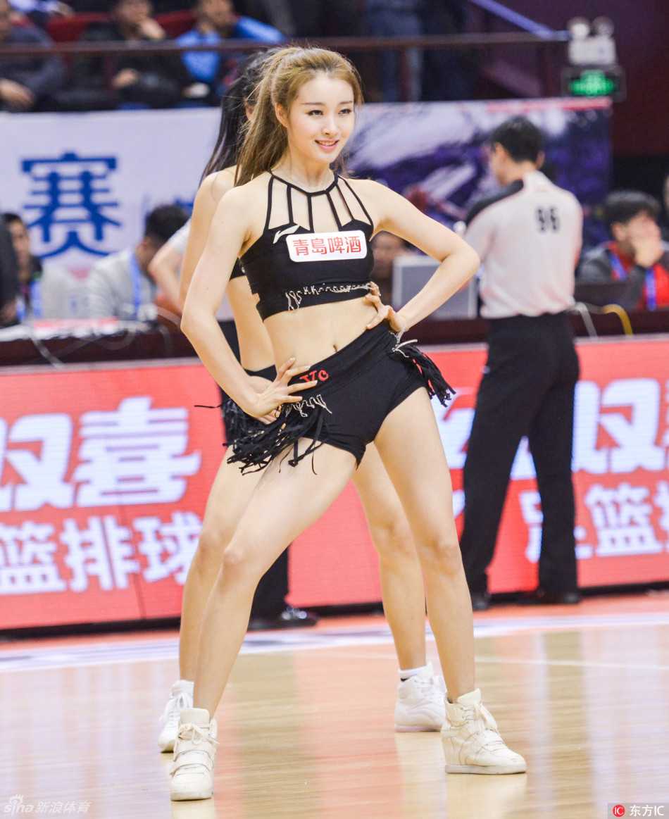 镜头拉近，一位面带甜美微笑的宝贝正对着观众席挥手互动，她的妆容精致，眼神中充满自信与热情，仿佛在用无声的语言为每一位到场球迷加油打气。