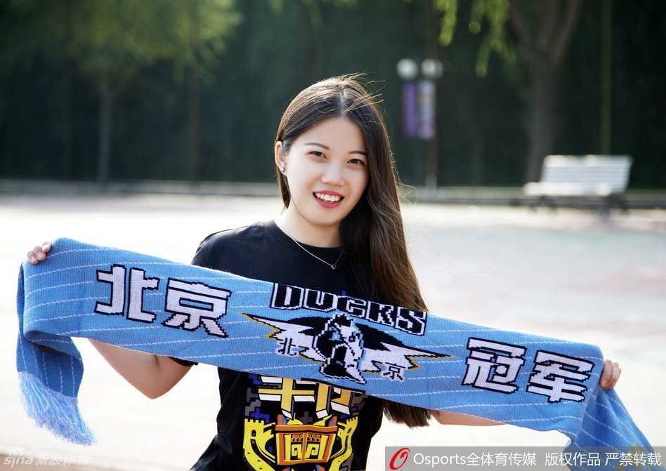 冬日暖阳下，一位长发及腰的北京女孩在首钢篮球中心外，露出灿烂笑容，她拉举着助威横幅，眼神中满是对主队必胜的信念。