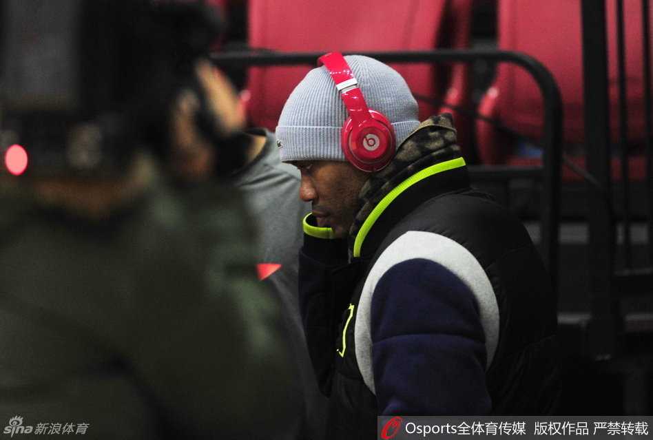 大外援莫里斯身穿灰色套头衫站在场边，神情严肃，他在内线需要面对布拉切和周琦的轮番冲击，眼神中透露出思索与坚定。
