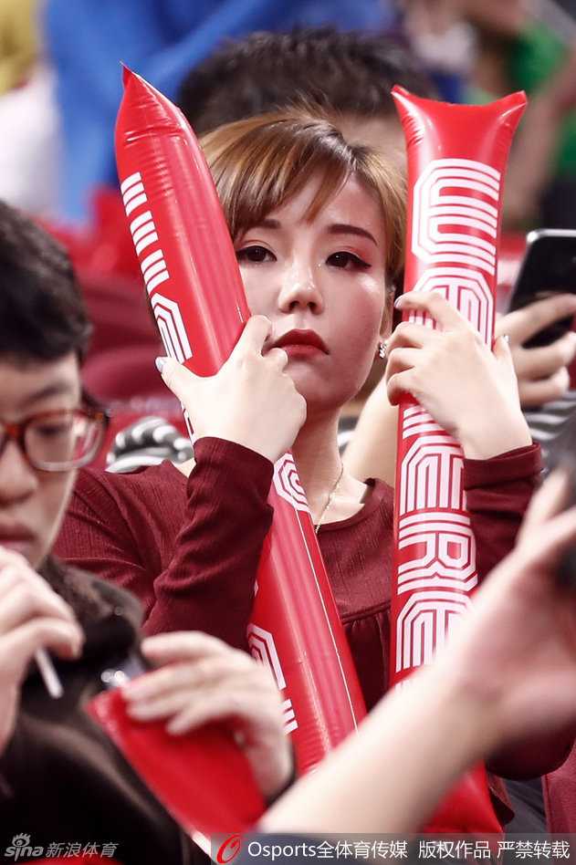 她轻轻举起充气棒抵在脸颊旁，眼神中透露出一丝俏皮与灵动，即便在嘈杂的球场看台上，那份清新脱俗的气质依然让她成为镜头的焦点。