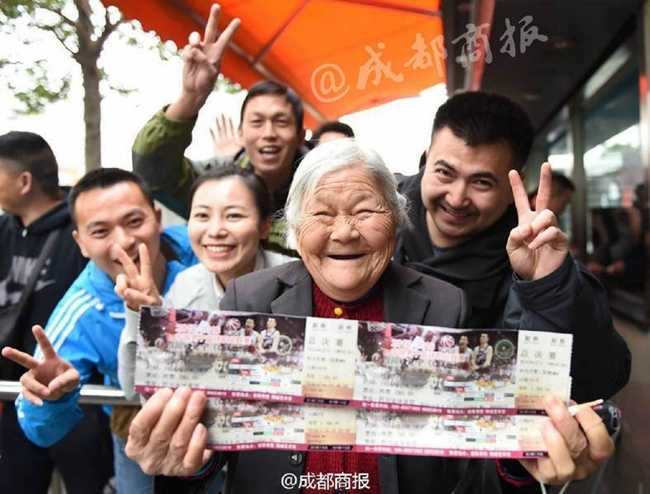 在拥挤的购票长龙中，一位不愿透露姓名的热心女球迷正弯下腰与维持秩序的民警沟通，她手指着队伍中步履蹒跚的老奶奶，眼神中满是担忧与关切，希望能为这位排了六小时队的老人争取一个特殊照顾。