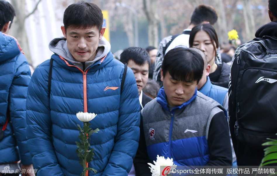 南京冬日阴郁的天空下，江苏肯帝亚的队员们身着深色外套，在五台山丛葬地的纪念碑前整齐列队，眼神低垂，面容写满了对历史的敬畏与沉重。