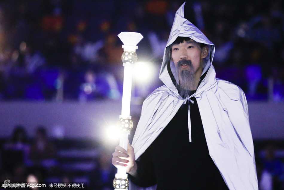 周琦与多名舞者同台表演，他手持金色魔杖神情专注，巨大的假胡子随着头部转动而微微摆动，营造出神秘而庄重的舞台氛围。