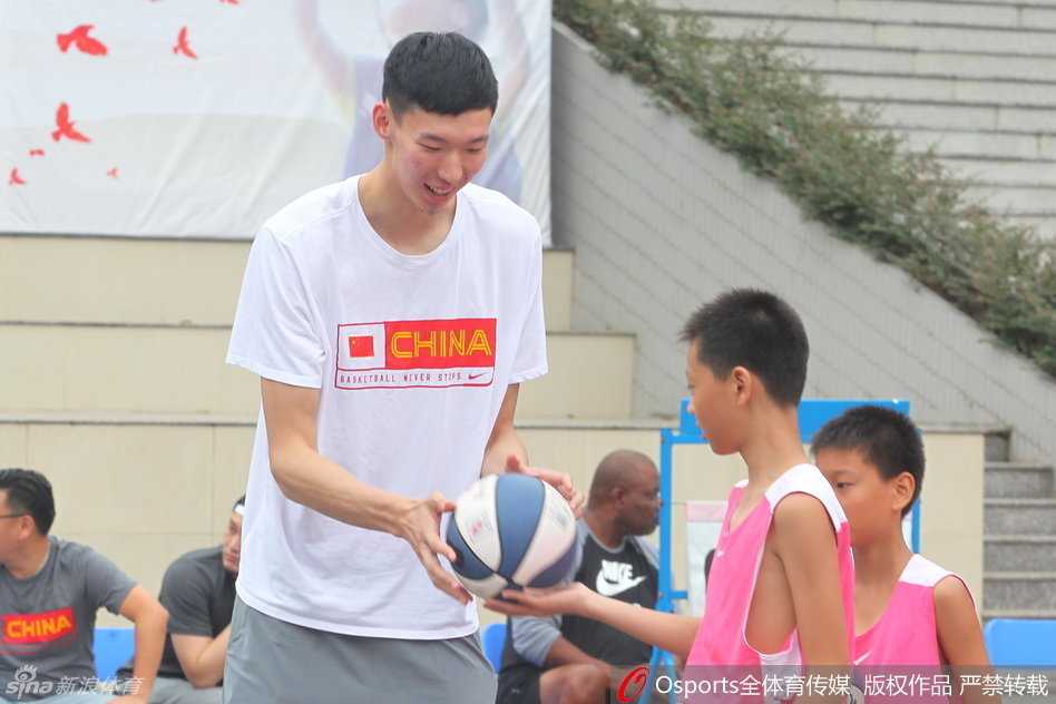 两位充满活力的NBA新秀面带微笑，主动弯下腰与面前的小球员进行轻松愉快的击掌互动。