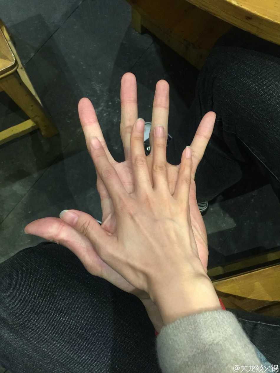 火锅升腾的热气模糊了背景，阿联耐心地配合着店员的合影请求。他微微屈膝低头，眼神温和地看向镜头，尽量让自己与身边的女店员处于同一画面中。女店员脸上洋溢着见到偶像的灿烂笑容，两人之间简单的互动充满了温情。