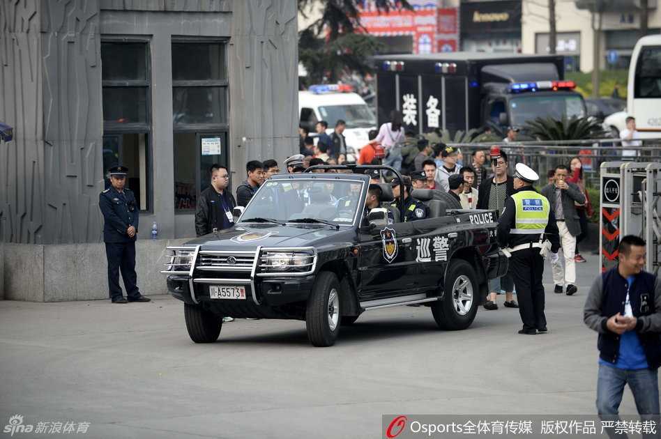 数辆黑白相间的特警车辆呈战术队形排列，车顶警灯无声闪烁，身着防弹背心的特警队员们站在车旁，构成一道牢不可破的钢铁防线。