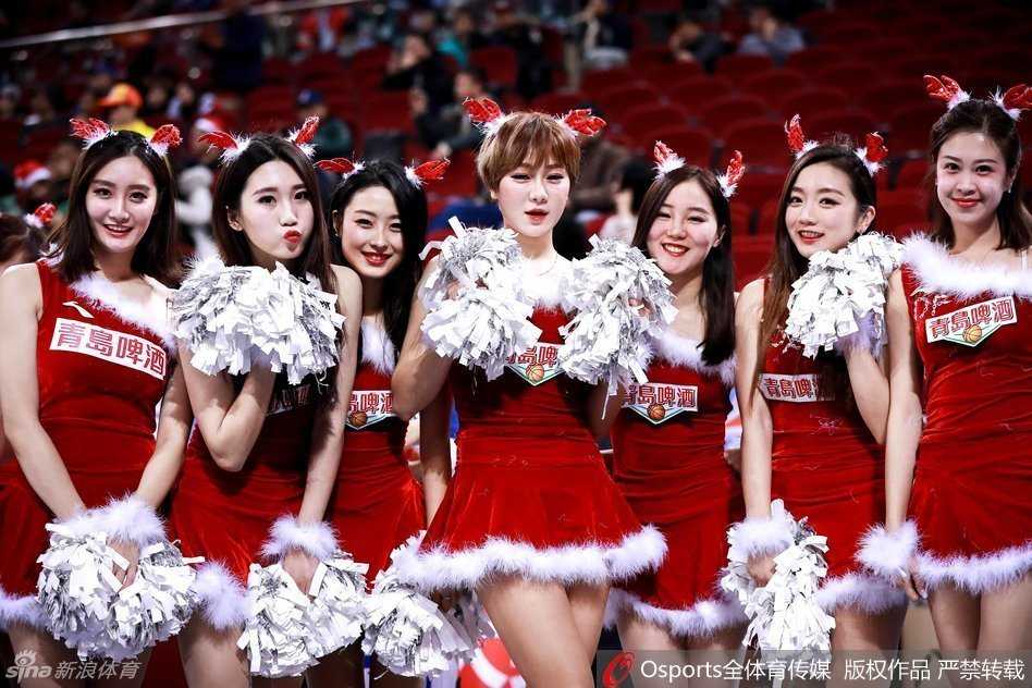 一位拉拉队员戴着闪闪发光的圣诞头饰，对着镜头露出甜美的微笑，身后的队友们形成虚化的背景，充满了青春的活力。