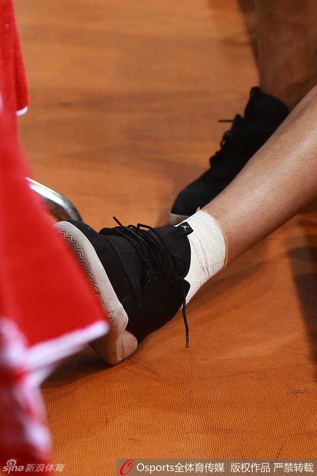 李慕豪孤独地坐在场边球员通道的台阶上，双手抱膝，目光凝视着远方正在庆祝的队友，仿佛游离于喧嚣之外。