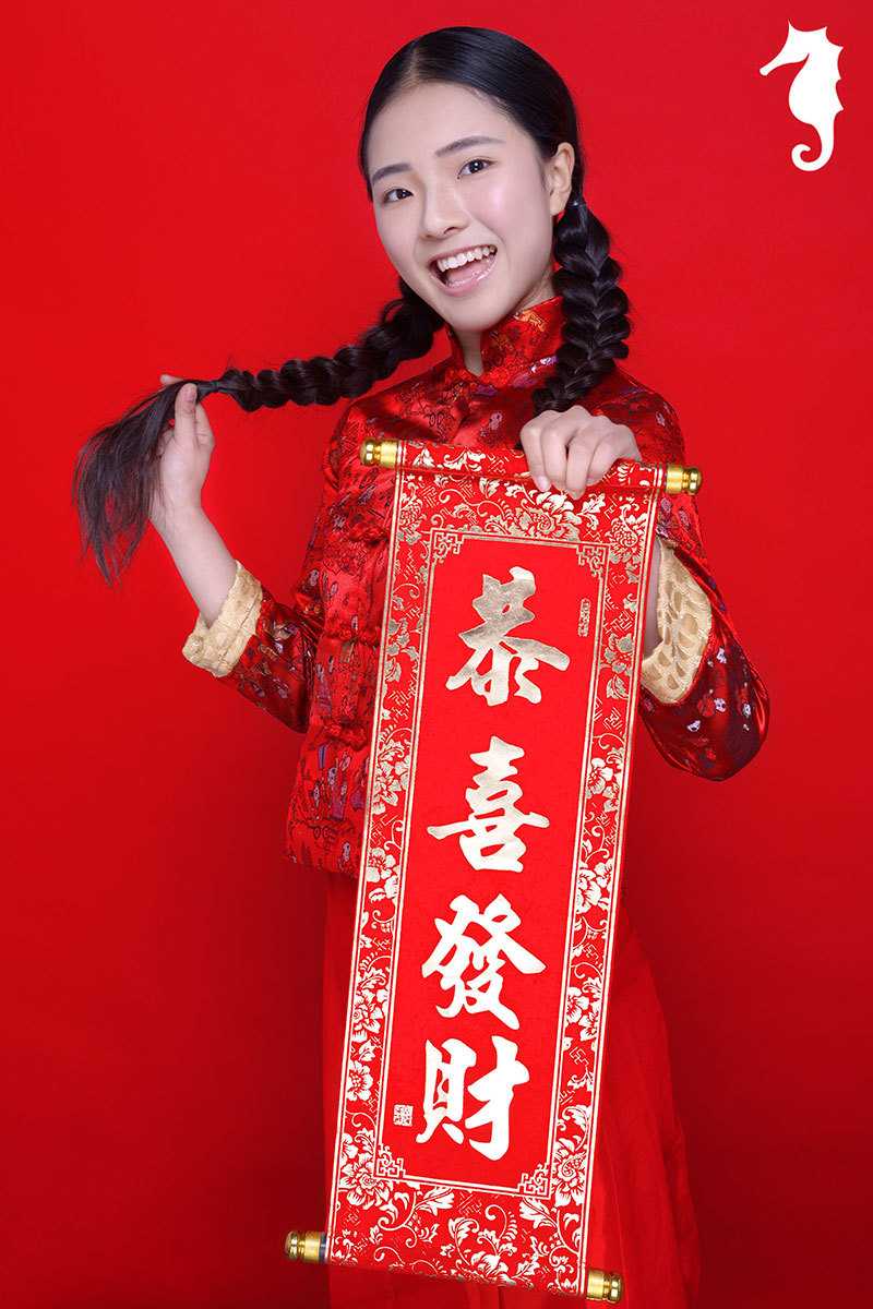 身穿精致刺绣唐装的宝贝眼神俏皮地斜瞥一侧，嘴角微翘，一副精灵古怪的机灵样，仿佛在琢磨着新年捣蛋的小计划