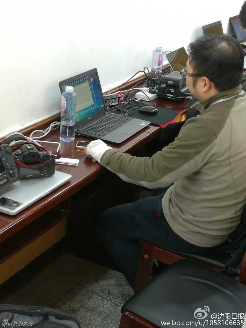 一位女记者正用缠着绷带的手指向电脑屏幕，似乎在与同事讨论稿件。白色的绷带与她专注工作的神情形成鲜明对比，仿佛在说：无论场外有多少纷扰，报道真相的手永远不会停歇。