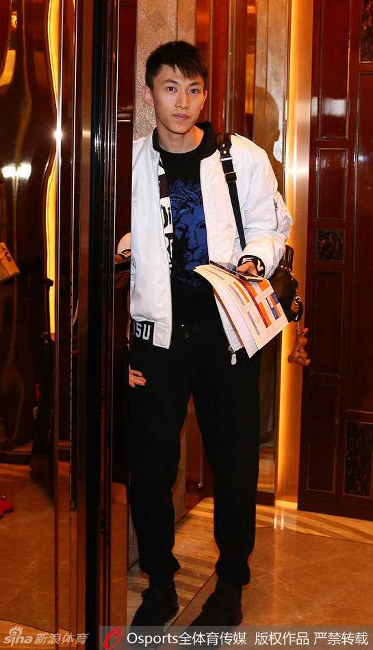 身穿深色休闲装的刘晓宇抵达酒店大堂，面对镜头露出温暖而谦逊的微笑，眼神中透着回家的亲切感。