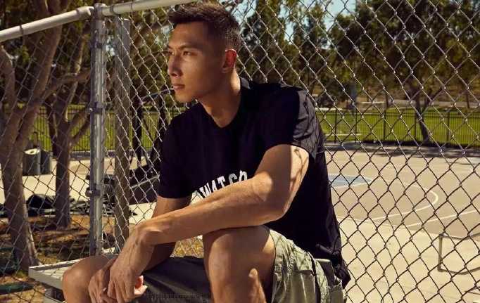 易建联身着简约白色T恤，坐在高脚椅上，双手交叉置于膝前，姿态放松却难掩与生俱来的强大气场，眼神中透着从容与坚定。