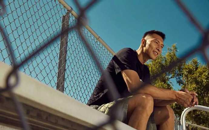 易建联身穿深色休闲装，双手插袋，目光深邃地凝视前方，背景的光影勾勒出他挺拔如松的身形，酷劲十足。