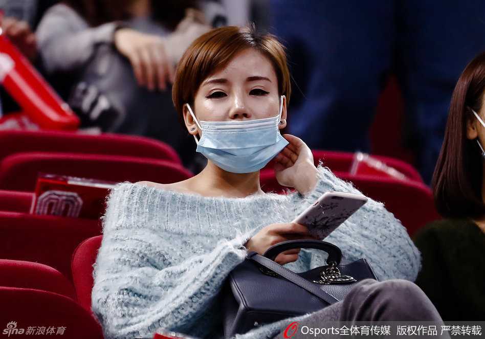 随着比赛进入白热化，她的神情也变得专注而紧张，微微侧头望向场内，即便戴着口罩也能感受到她屏息凝神的心情。