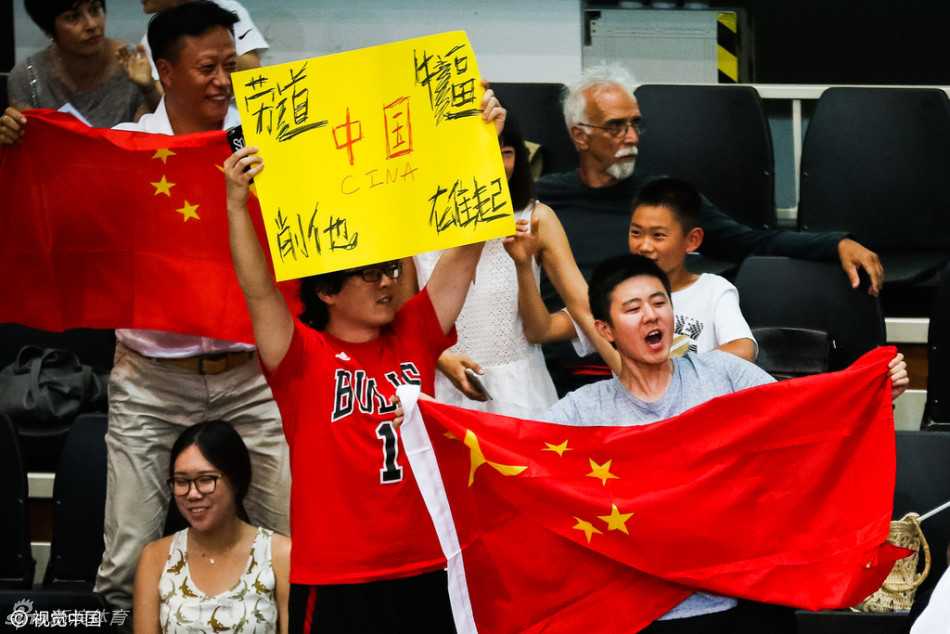 看台上的中国球迷们挥舞着五星红旗，脸上画着国旗图案，神情专注地为场上的每一次精彩表现呐喊助威