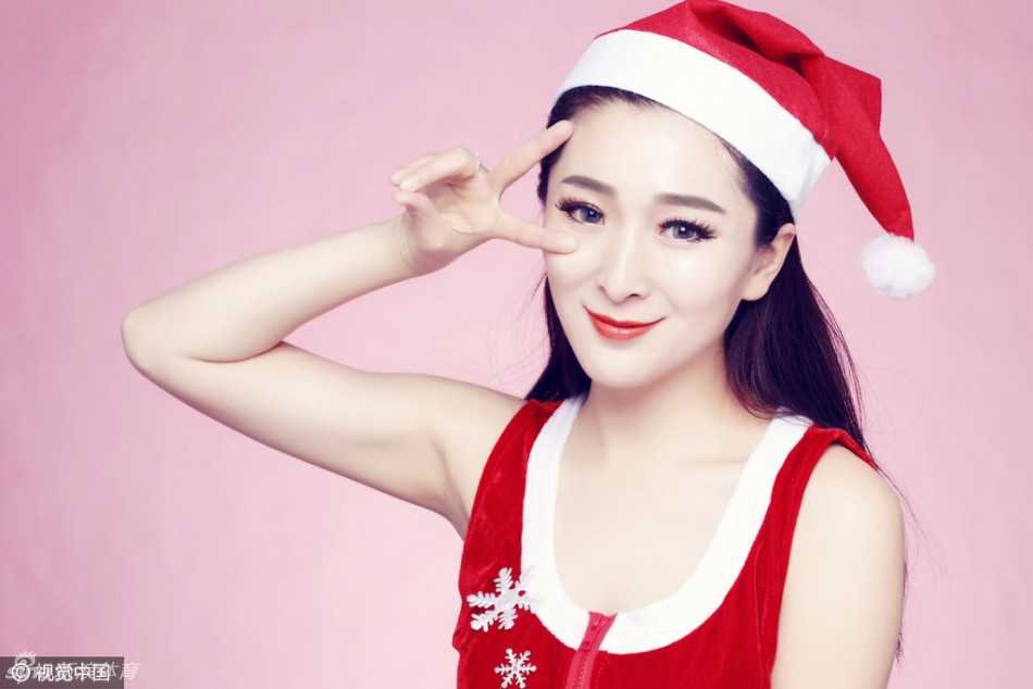 热辣的圣诞装扮完美勾勒出啦啦队员的曼妙身姿，她手持金色啦啦花，眼神中透着一丝自信与性感，在红色背景的映衬下，宛如一份等待拆封的节日礼物。