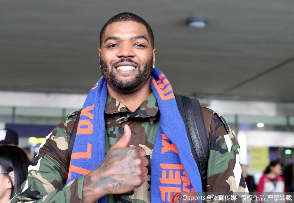 约什·史密斯在酒店大堂遇见队友哈达迪，他像个小兄弟一样跟在哈达迪身后，脸上带着谦逊的笑容，两人正低声交流着什么。