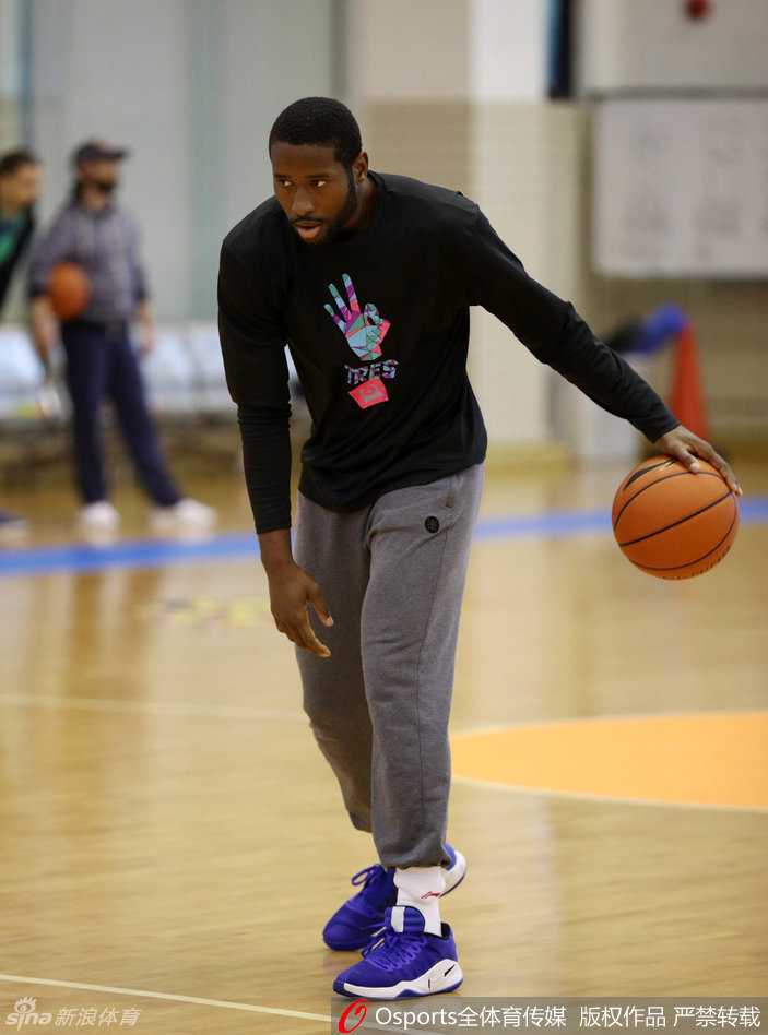 易建联在训练中弯腰低姿全神贯注地运球，高大的身躯展现出如同后卫般的灵活与协调，汗水已浸湿了他的训练背心。