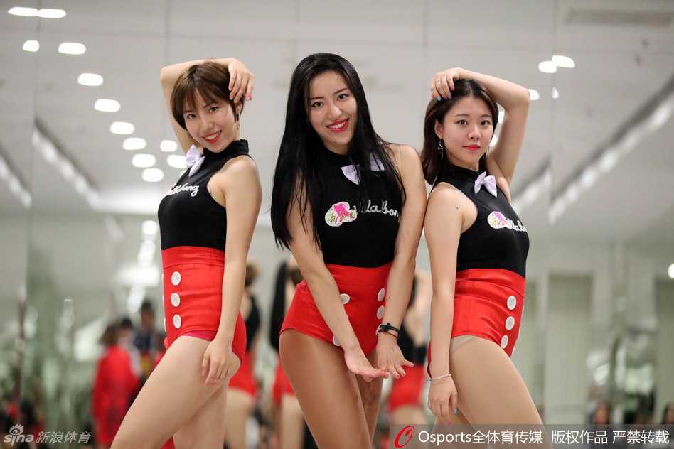 篮球宝贝亲密无间地配合，纤细有力的腰身作为支撑点，队友在空中轻松掰腿摆出高难度姿势，黑红装束在灯光下格外耀眼