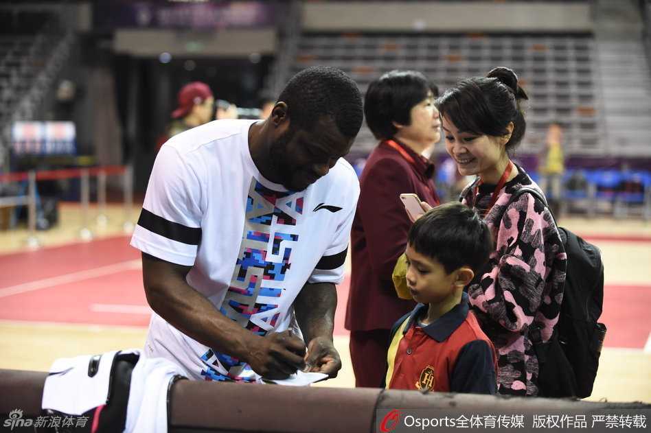 广东队外援拜纳姆耐心地为场边伸长手臂的小球迷签名，虽然语言不通，但篮球拉近了彼此的距离。
