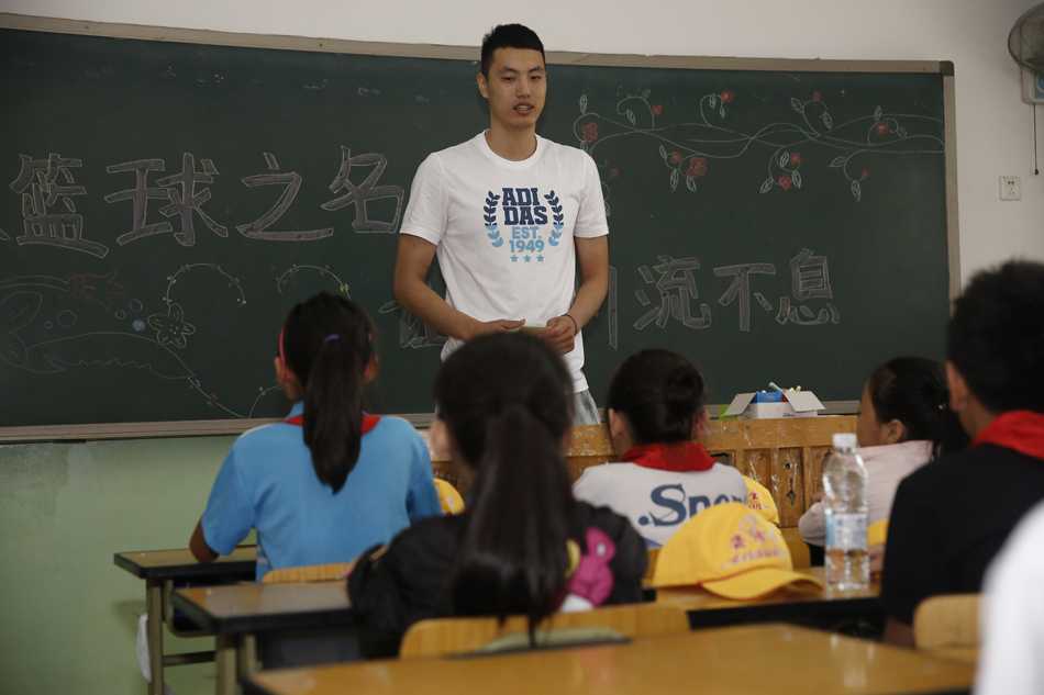 翟晓川在简陋的教室里与孩子们围坐在一起，他耐心地倾听一位小女孩说话，眼神温柔，孩子们紧紧靠在他身边，毫无距离感