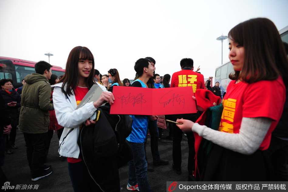 西热力江被几位年轻球迷簇拥着前行，他神情轻松，正在与身边的球迷进行简短的交谈。