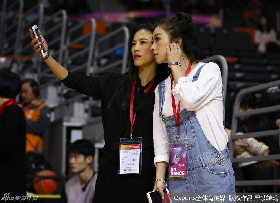 赛场边，两位记录赛场的女记者趁工作间隙并肩而立，对着镜头绽放出如姐妹般亲昵无间的明媚笑容，眼波流转间满是青春活力。