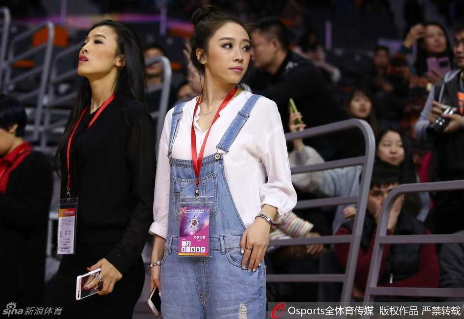 身背媒体包的女孩双手捧着手机，屏幕上正回放着刚拍摄的画面，她嘴角含笑的专注神情，透露出对所记录内容的由衷喜爱。